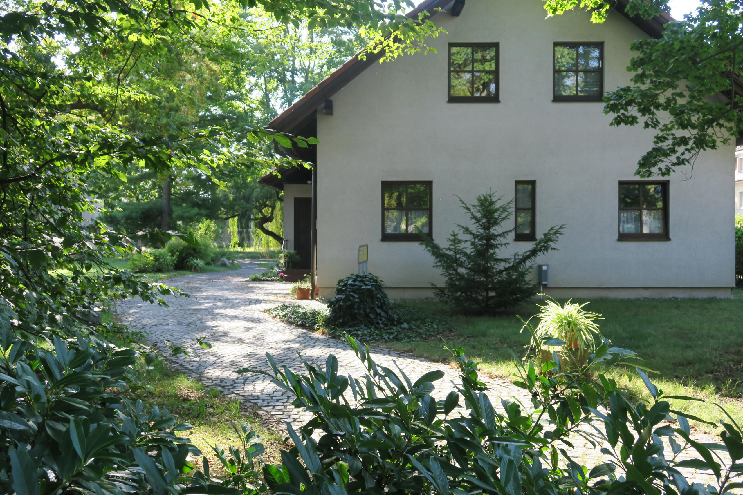 Zahnarztpraxis im Haus, erreicht über einen gepflasterten Weg